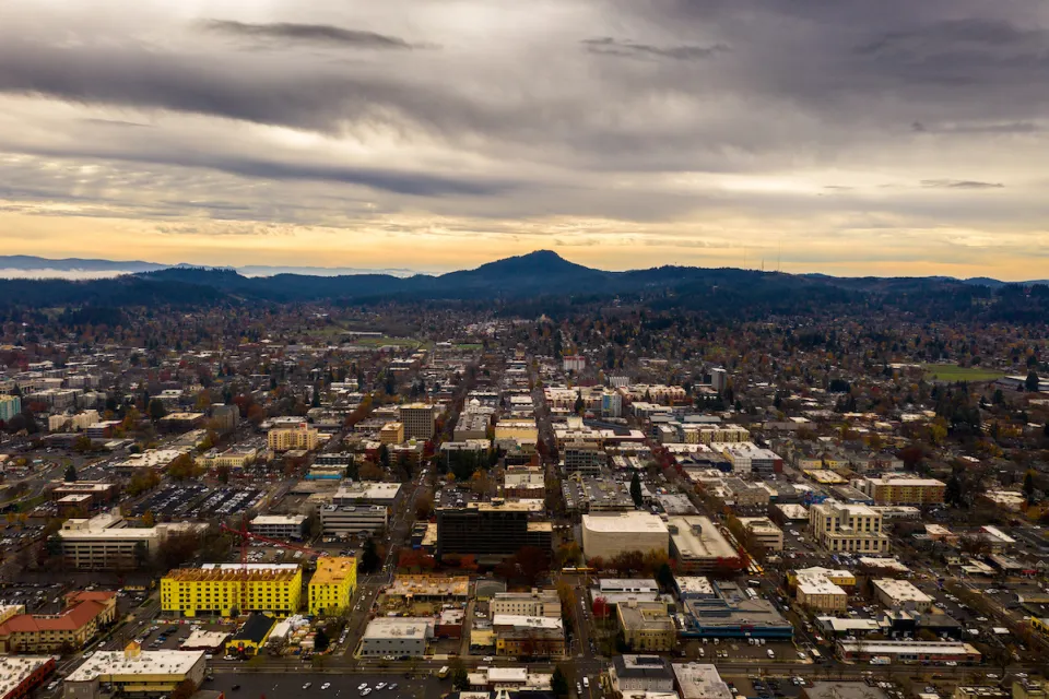 Aerial view of Eugene, Oregon at dusk with mountains in background.